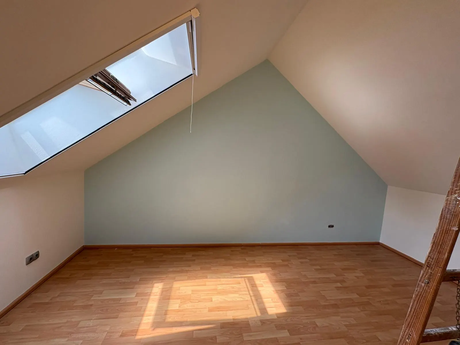 Frisch gestrichenes Dachgeschoss mit farbig abgesetzter Giebelwand und Dachfenster