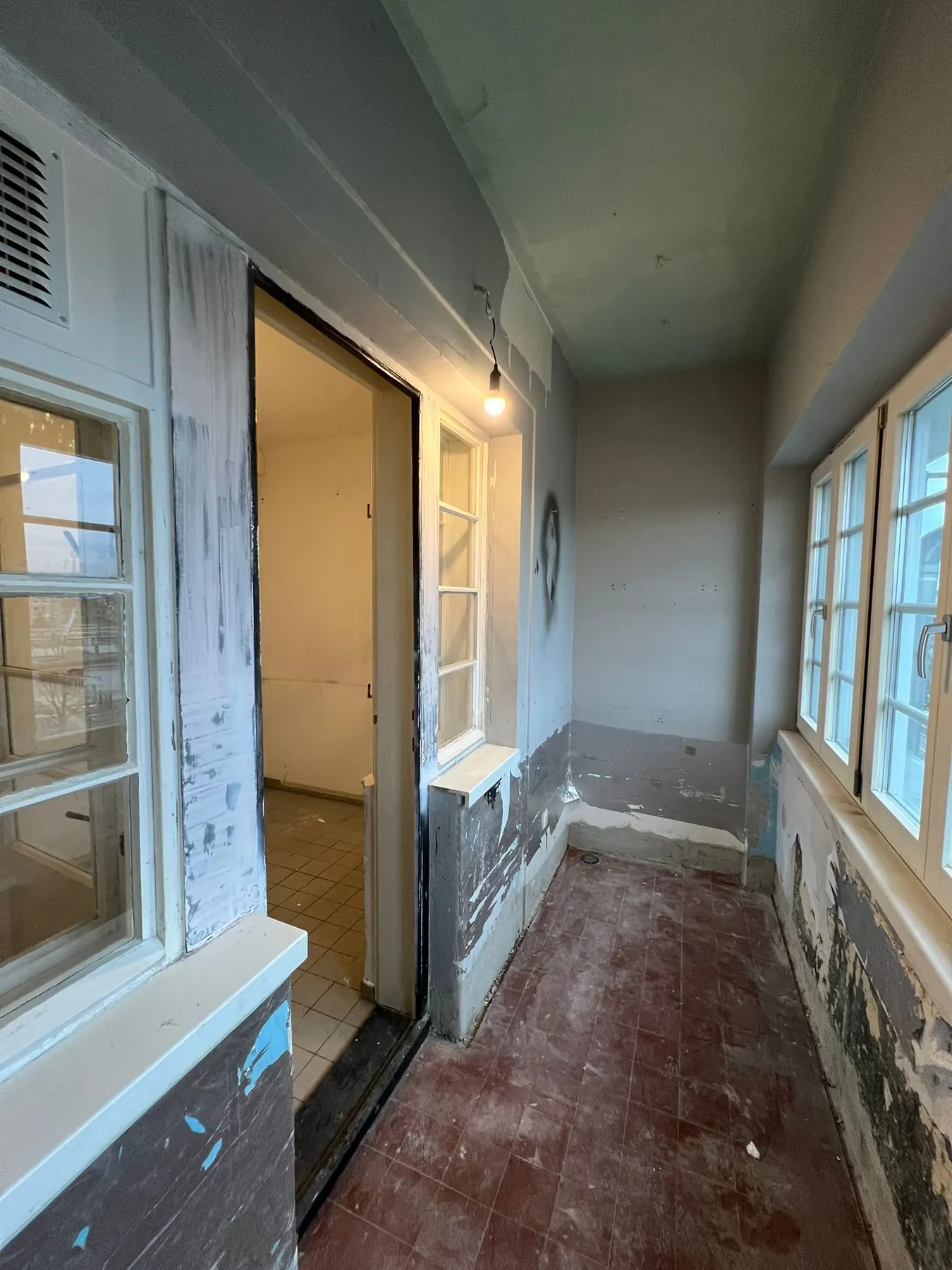 Vorher: Loggia mit abgeplatzter Farbe an Wänden und Fensterrahmen